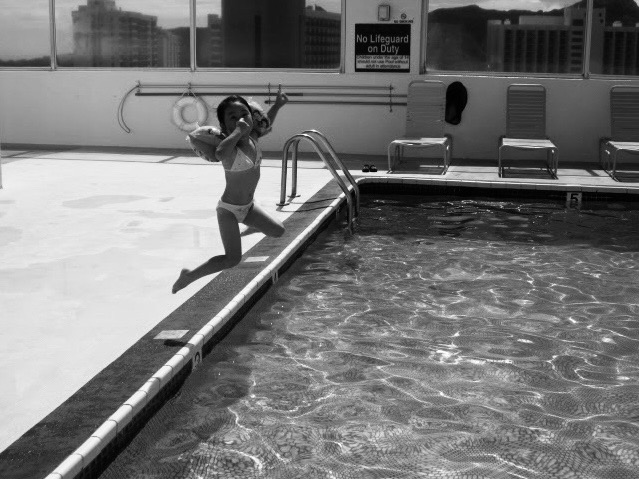 A person jumping beside a swimming pool.